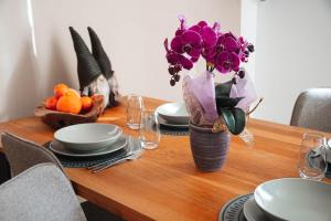 a dining room table with a vase of purple flowers at Alpine Green Apartment 2026 in Sondrio +9 photos