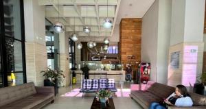 a woman sitting on a couch in a lobby at Crystal Place Flat 509 in Goiânia +7 photos