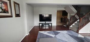 a living room with a television and a staircase at Townhome in Ranson, WV in Ranson