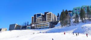 a group of people on a snow covered slope in front of a building at Ski & Spa Bjelašnica in Bjelašnica