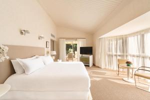 a bedroom with a large white bed and a television at Locanda Punta Del Este in Punta del Este