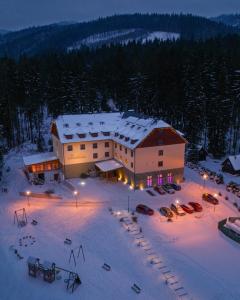 a large building in the snow at night at Wellness Hotel pod Kyčmolem in Horní Lomná