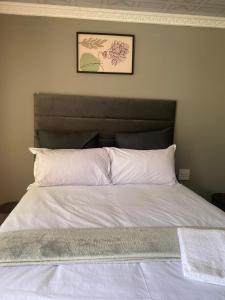a bed with white sheets and a picture on the wall at Namhla Guest House in Nongoma