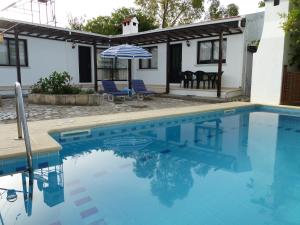 a swimming pool with an umbrella next to a house at Hidden Cottage in Kyrenia