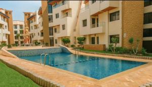 a swimming pool in front of a building at Résidence Macha'allah in Ben Slimane