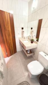 a bathroom with a toilet and a sink and a mirror at Milho Ventura II, Vila Pôr do Sol in Sêrro