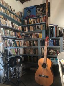 a guitar in a room with a lot of books at Los Albergues in Pitres