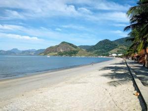 a beach with palm trees and the ocean at Casa Ampla Vila Muriqui in Vila Muriqui