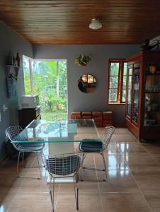 a dining room with a glass table and chairs at Sítio em São Bonifácio in Alto Rio Bravo
