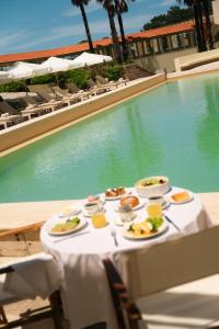 a table with plates of food next to a swimming pool at Locanda Punta Del Este in Punta del Este