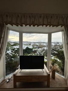 a living room with a large window with a flat screen tv at Derbyshire Holiday Cottages in Holmesfield +8 photos