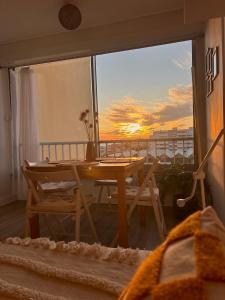 a table and chairs on a balcony with a sunset at À 1min à pied de la mer, studio lumineux & cosy in Carnon-Plage