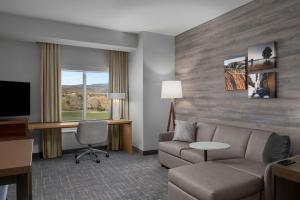 a hotel room with a couch and a desk and a tv at Residence Inn by Marriott St. George in Washington