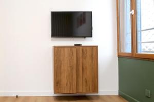 a flat screen tv on a wall with a wooden cabinet at Superbe appartement avec écran géant in Tarbes