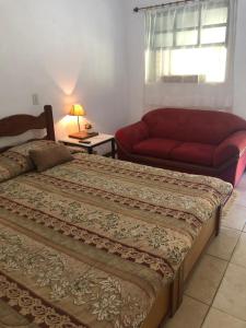 a bedroom with a large bed and a couch at Pousada do Campo in Ipiabas
