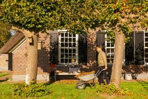 a man pushing a wheelbarrow in front of a house at De Rheezer Kamer in Hardenberg
