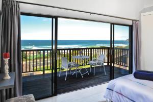 a bedroom with a balcony with a view of the ocean at Sea La Vie Beach House in Wilderness