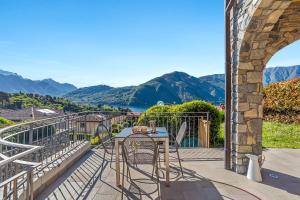 a balcony with a table and chairs and mountains at Villa Tremezzo in Tremezzo