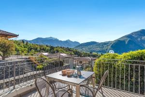 a table and chairs on a balcony with mountains at Villa Tremezzo in Tremezzo