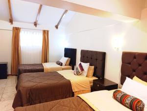 a hotel room with three beds in a room at Hotel Humantay lodge Ollantaytambo in Ollantaytambo