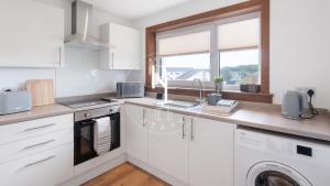 a white kitchen with a sink and a dishwasher at The Den at Braehead in Cruden Bay