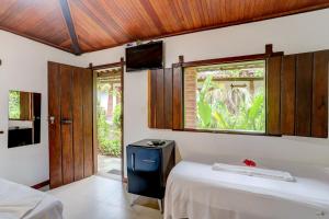 a bedroom with a bed and a window and a tv at Pousada Piratas in Itacaré