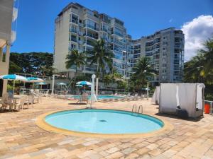 a swimming pool in front of a large building at Encanto da Praia LUXO Ap 2 qts Pe na Areia Camboinhas in Niterói