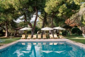 a swimming pool with chairs and umbrellas at Masia Can Pares in Sant Pere de Ribes