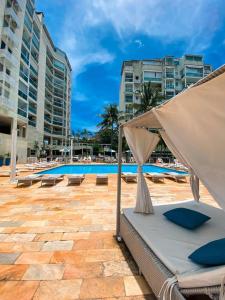 a bed with a canopy in front of a pool at Encanto da Praia LUXO Ap 2 qts Pe na Areia Camboinhas in Niterói