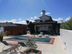 a villa with a swimming pool in front of a house at Espaço Roteiro de Mimos in São Vicente Ferreira