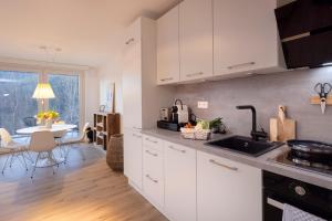 a kitchen with white cabinets and a dining room with a table at Hermine, Black Forest Retreat, mit Sonnenterrasse in Baiersbronn