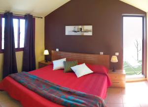 a bedroom with a red bed with two pillows at Residential Majada Apartments in Puerto del Rosario