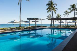 a swimming pool with chairs and umbrellas and the ocean at Coral Sea Resort in Airlie Beach +36 photos