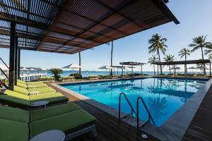 a pool with chairs and the ocean in the background at Coral Sea Resort in Airlie Beach