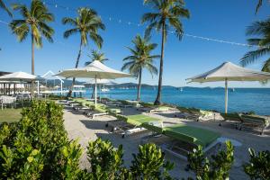 a bunch of lounge chairs and umbrellas on a beach at Coral Sea Resort in Airlie Beach