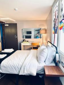 a bedroom with a bed and a desk and a window at Guest And The City in Brighton & Hove