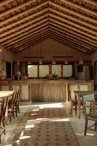a dining room with wooden ceilings and tables and chairs at Casa do Amor Caraíva in Caraíva