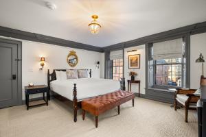 a bedroom with a bed and a chair and windows at The Davenport Inn in Portsmouth