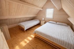 a attic bedroom with two beds and a window at Domeczki Blaneczki Wicie - domki letniskowe nad morzem in Wicie