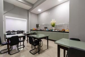 a dining room with tables and chairs and a kitchen at GB Hotéis Foz Centro in Foz do Iguaçu