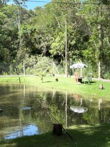 a table and an umbrella next to a pond at Pesqueiro & Pousada Beatriz in Piedade