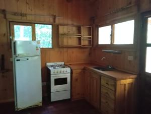 a kitchen with a white stove and a refrigerator at Chacra Mariposas in Oberá