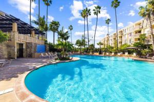 a large swimming pool in a hotel with palm trees at Beachfront Resort-sunset views deck & luxe king in Oceanside