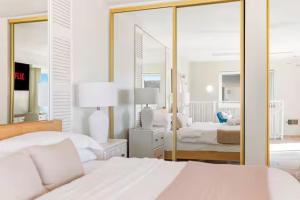 a bedroom with two beds and a large mirror at Beachfront Resort-sunset views deck & luxe king in Oceanside +23 photos