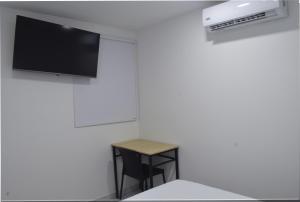 a room with a table and a tv on a wall at Hotel Casa Camoa in Villavicencio