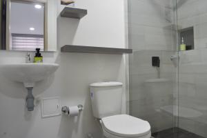 a bathroom with a toilet and a sink and a shower at Hotel Casa Camoa in Villavicencio