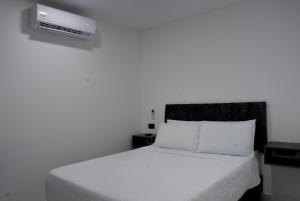 a bedroom with a bed with a white bedspread at Hotel Casa Camoa in Villavicencio