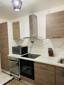 a kitchen with a stove and a microwave at BY NEPTUNE - Appartement Rustique JACUZZI in Bondy