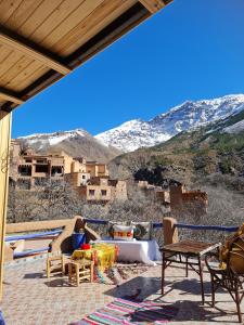 a woman sitting on a patio with mountains in the background at Dar Benhoussa Imlil in Imlil +25 photos