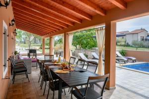 a patio with a table and chairs and a pool at Villa Percan - Spacious Family Home with Private Pool on a 4000 Square Meter Plot in Krnica